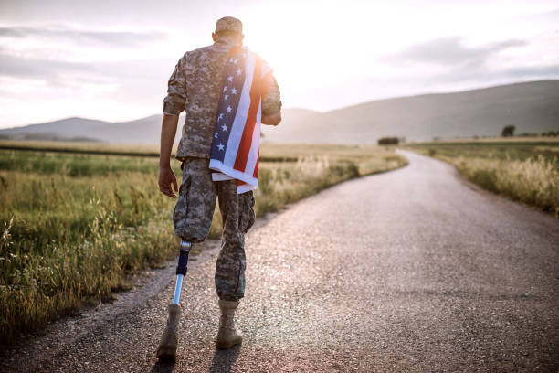 Rear View Of Young Amputee Soldier Walking Road Wearing American Flag