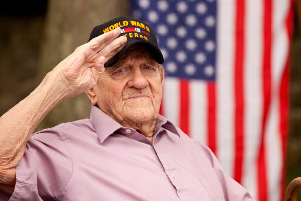 Hand salute and looking directly in to camera with concerned look on his face, with US flag in background. Image shot with Canon 5D Mark2, EF 70-200 f2.8L USM lens, natural light.